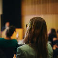 The back of a woman's head listening at a conference