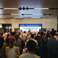 A crowd watching a speaker on raised staging