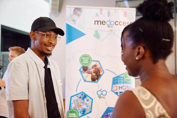 Medaccess founder stood next to his stand chatting to a Demo Night attendee