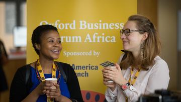 Oxford Business Forum Africa Two women talking and standing in front of a Oxford Business Forum Africa banner